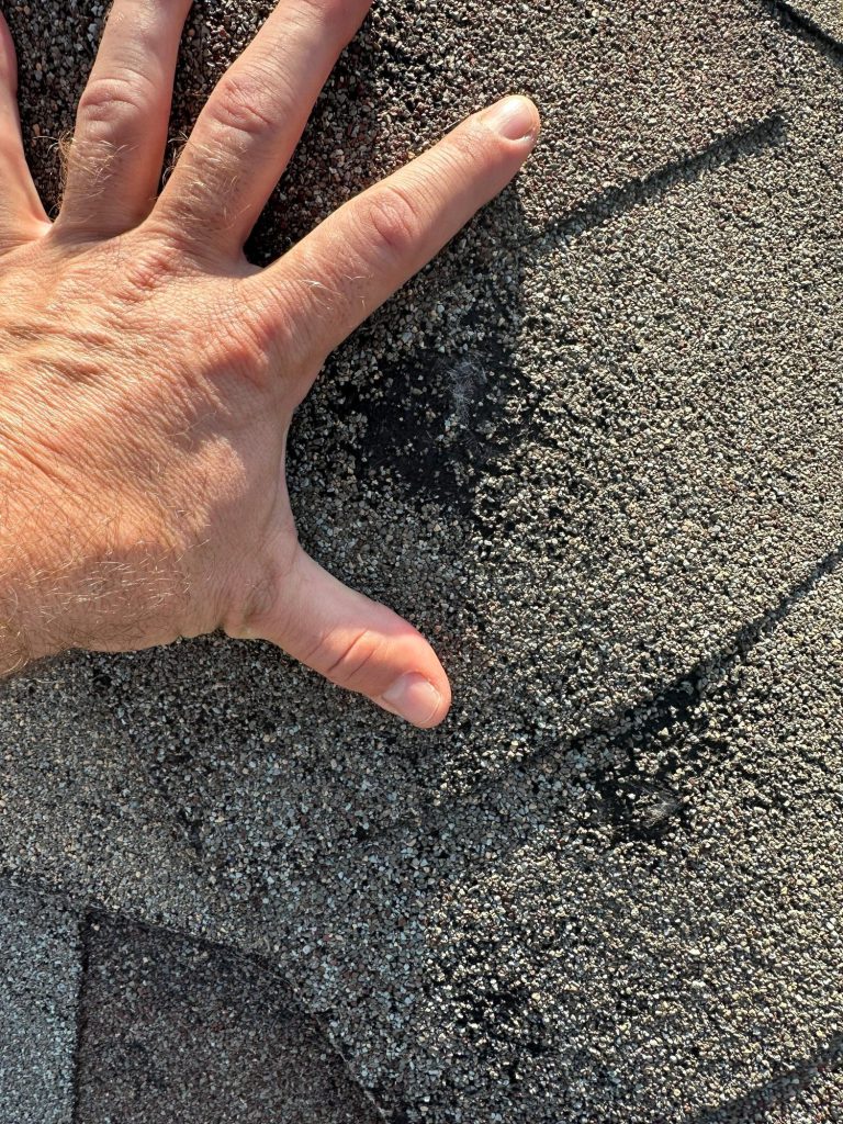 Inspector checking a hail bruise on an asphalt shingle
