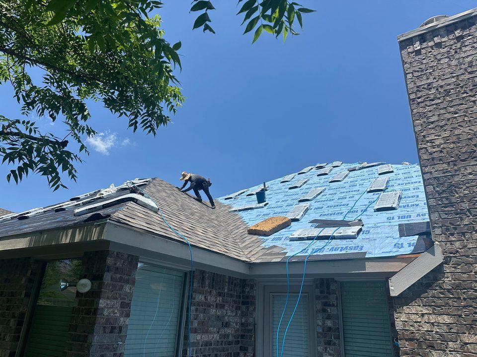 Roofing crew installing synthetic underlayment on a stone home
