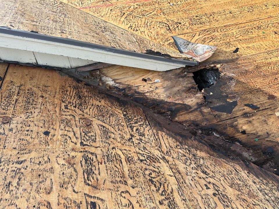 Rotted decking at a roof eave exposed during tear-off